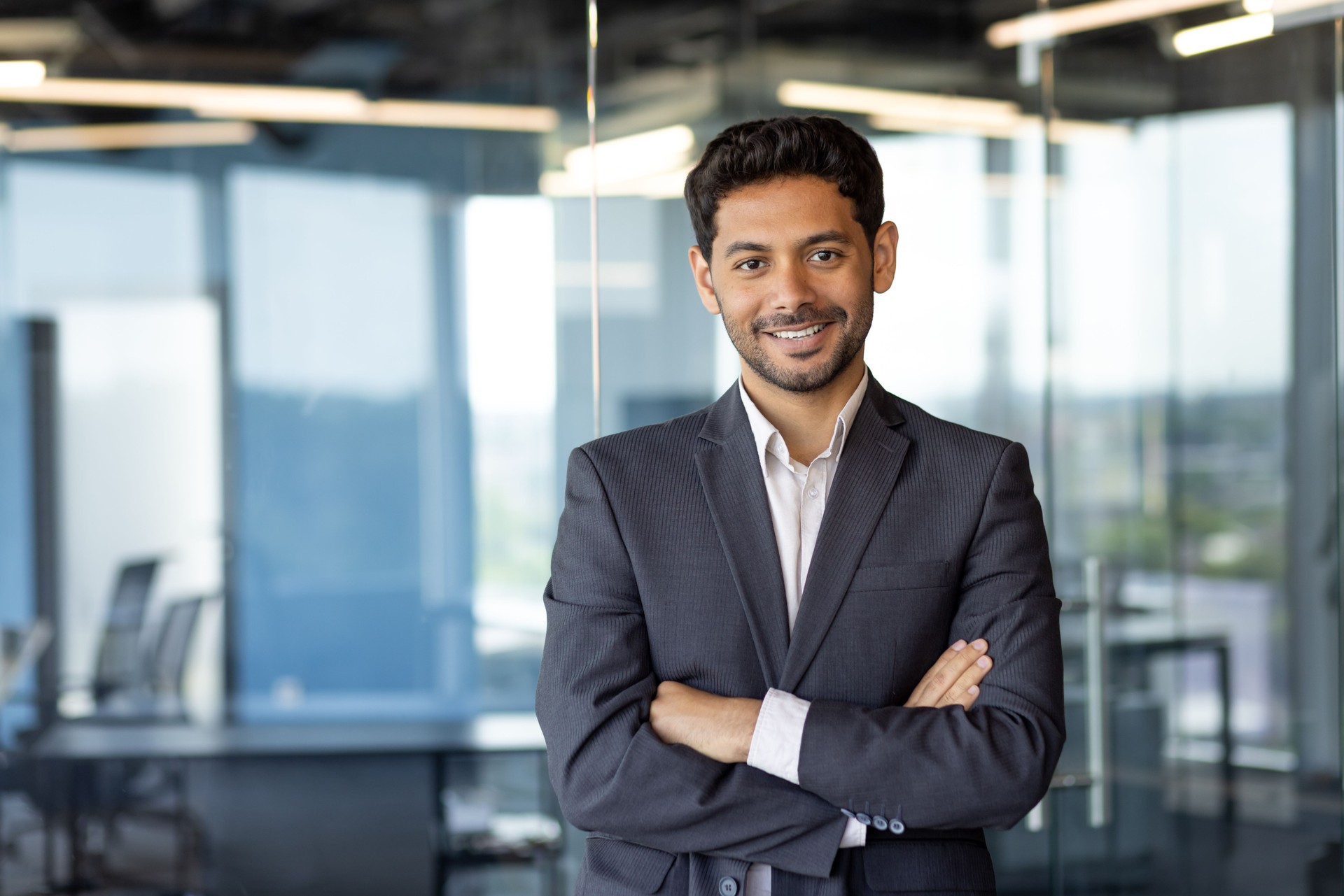 Portrait of successful mature boss, senior businessman in business suit looking at camera and smiling, man with crossed arms working inside modern office building.